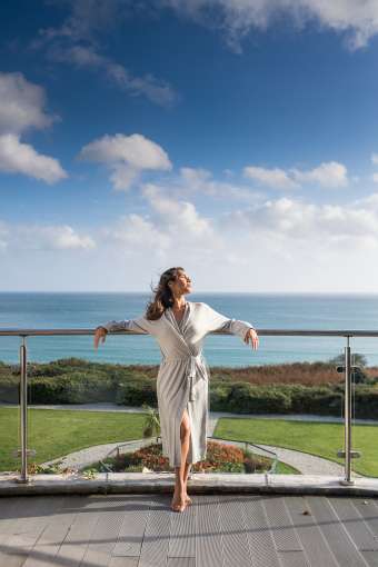 Woman on balcony with sea in background relaxing