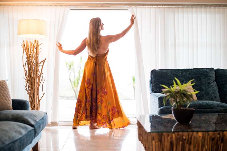 woman opening back curtains in apartment lounge