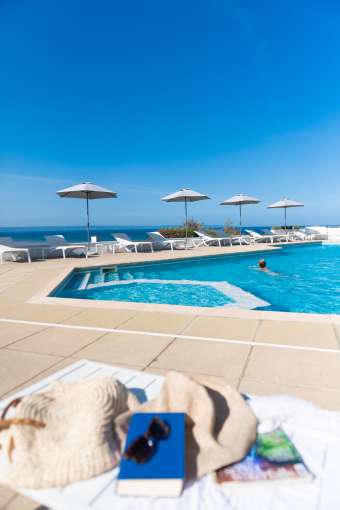 Outdoor pool on a sunny day with lady swimming in the pool