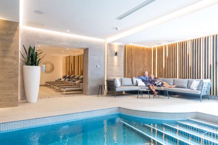 Couple relaxing on sofa by indoor pool