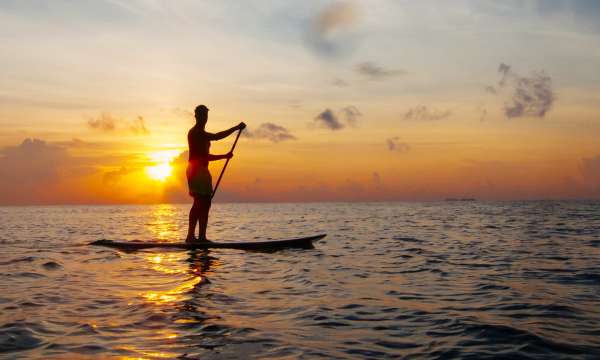 A paddle boarder on calm seas at sunset